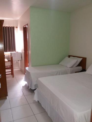 a bedroom with two beds and a table and a chair at Ipê Guaru Hotel in Guarulhos