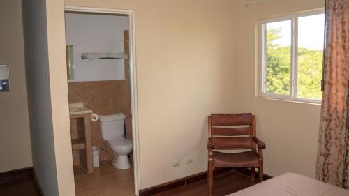 uma casa de banho com um WC, uma cadeira e uma janela. em LC17 La Cometa Center of Tamarindo 2bed+2.5bath em Tamarindo