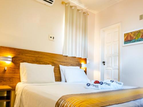 1 dormitorio con 1 cama con sábanas blancas y cabecero de madera en Pousada Manaia, en Morro de São Paulo
