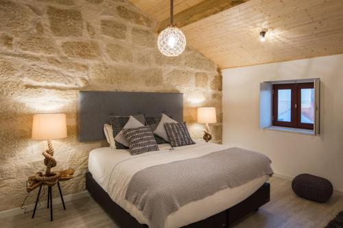 ポルトにあるPorto Deluxe Suitesの石壁のベッドルーム1室(大型ベッド1台付)