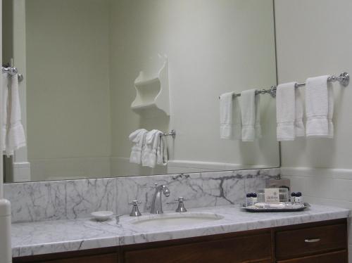 a bathroom with a sink, mirror and towel rack at Arizona Inn in Tucson