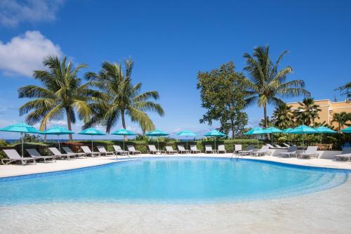 a swimming pool with chairs and umbrellas and palm trees at Beach View Hotel in Saint James