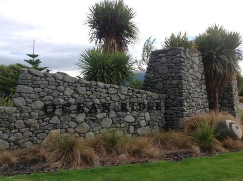 a stone wall with palm trees behind it at The Fairways Accommodation Kaikoura in Kaikoura