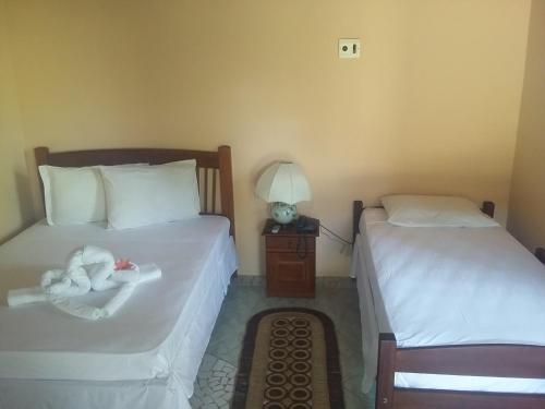 a bedroom with two beds and a table with a lamp at Barreirinhas - Chalé perto do restaurante Bambaê in Barreirinhas