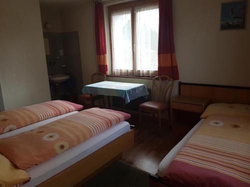 een kamer met 2 bedden, een tafel en een raam bij Hotel Simplon-Blick in Simplon Hospiz