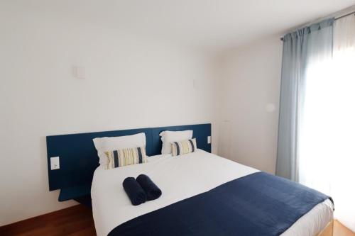 a bedroom with a large bed with black shoes on it at InnEsposende Sports Hostel in Esposende