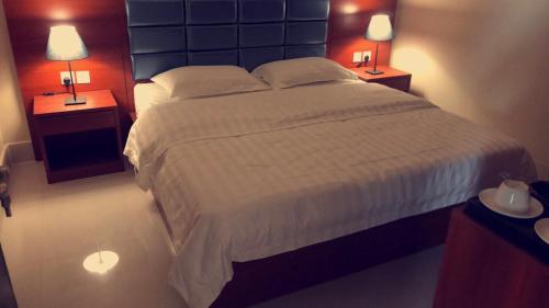 een slaapkamer met een groot wit bed met 2 lampen bij Durat Al Lith Chalet in Al Lith