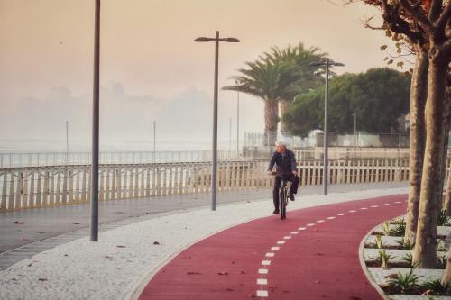 a person riding a bike on a sidewalk near the beach at InnEsposende Sports Hostel in Esposende