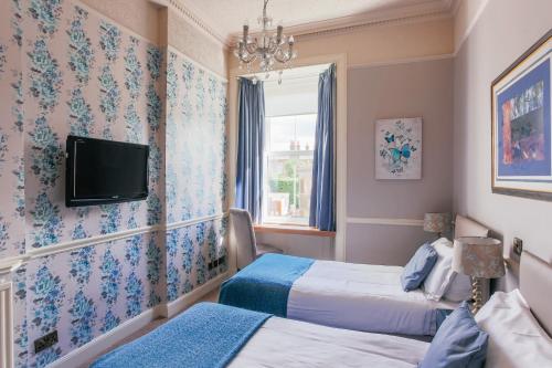 a room with two beds and a tv on the wall at Braid Hills Hotel in Edinburgh