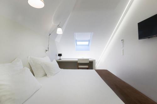 a bedroom with a white bed and a tv at Hotel Fabrica do Chocolate in Viana do Castelo