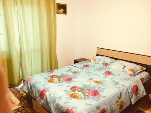 un letto con un piumone blu e fiori sopra di Villa Melania ad Azuga