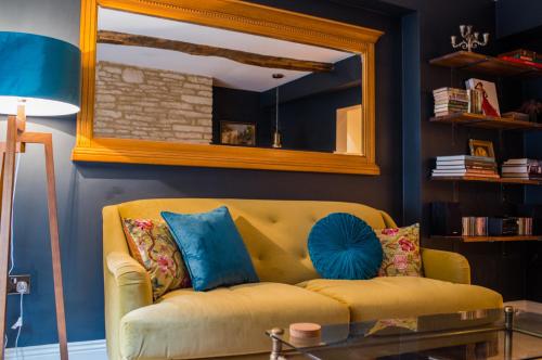 Sofá amarillo en la sala de estar con espejo en Cotswold Place en Cirencester