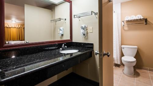 een badkamer met een wastafel, een toilet en een spiegel bij Rancho San Diego Inn & Suites in El Cajon