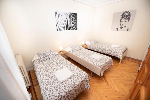 a room with two beds and a table at Espacios Blanco Santiago - con parking. in Valladolid