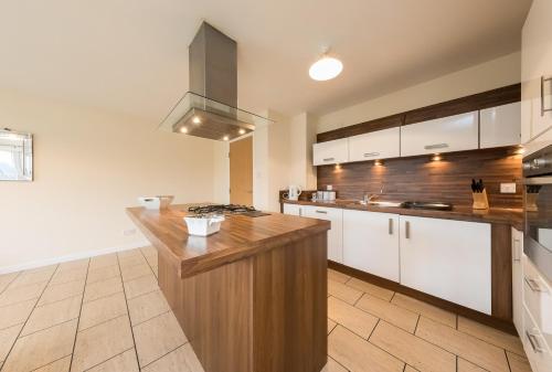 a large kitchen with white cabinets and a wooden counter top at The Broch, 1st Floor, Luxurious City Centre Apartment in Perth