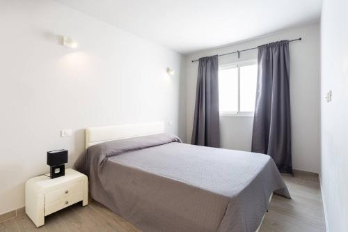 a white bedroom with a bed and a window at Torres del Sol in Arona