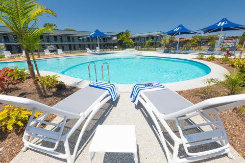 a swimming pool with two lounge chairs and a swimming pool at Hotel Forster in Forster