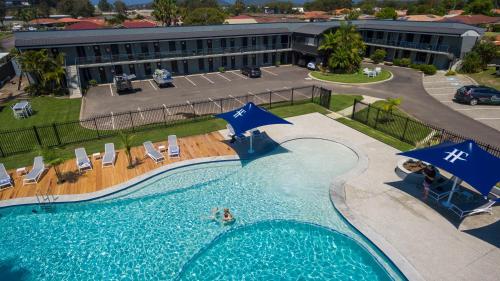 a swimming pool with blue umbrellas and chairs and a building at Hotel Forster in Forster