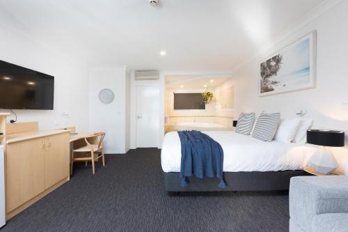 a hotel room with a large bed and a desk at Hotel Forster in Forster