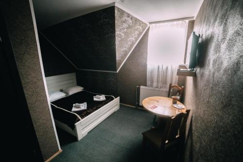 una pequeña habitación con una cama y una mesa en Alpin Hotel, en Bukovel