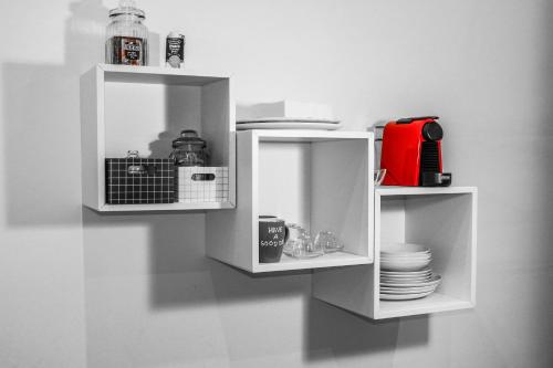 two white shelves on a wall with dishes at Le BB in Bari