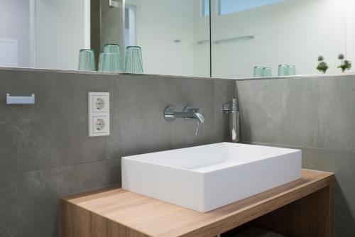 a bathroom with a white sink and a mirror at Suites MITTE - Aparthotel in Eisenach