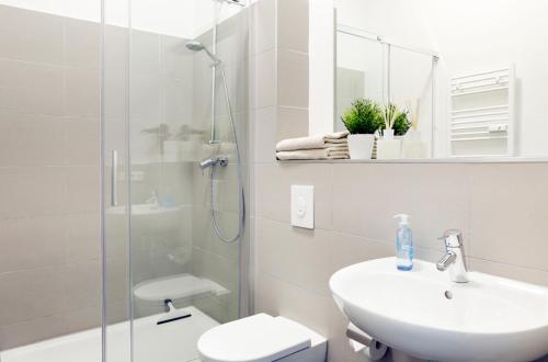 uma casa de banho branca com um lavatório e um chuveiro em SC 1 Cozy Family & Business Flair welcomes you - Rockchair Apartments em Berlim