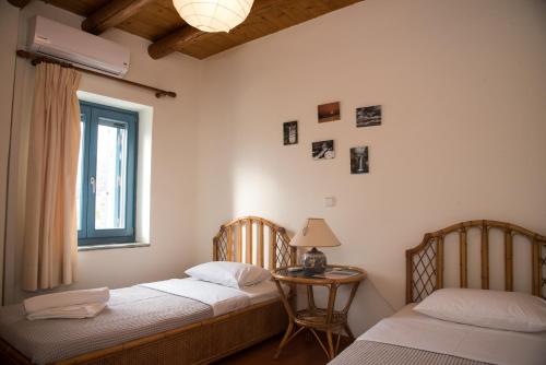 two beds in a room with a table and a window at Petra Traditional House in Episkopión