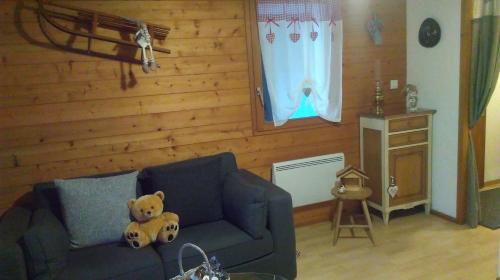 un ours en peluche assis sur un canapé dans un salon dans l'établissement village vosgien, à Gérardmer