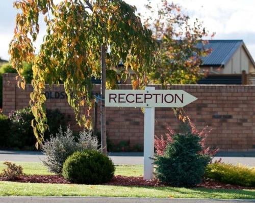 a white street sign in front of a house at BK's Chardonnay Motor Lodge in Masterton