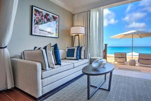 a living room with a couch and a view of the ocean at Fairmont Royal Pavilion Barbados Resort in Saint James