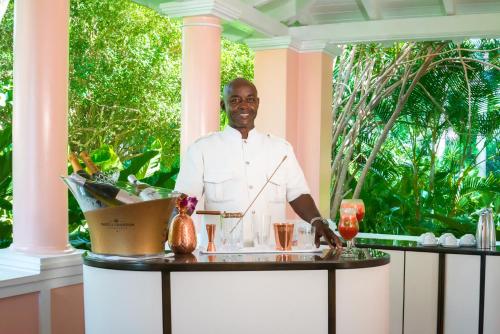 a man standing behind a table with drinks at Fairmont Royal Pavilion Barbados Resort in Saint James