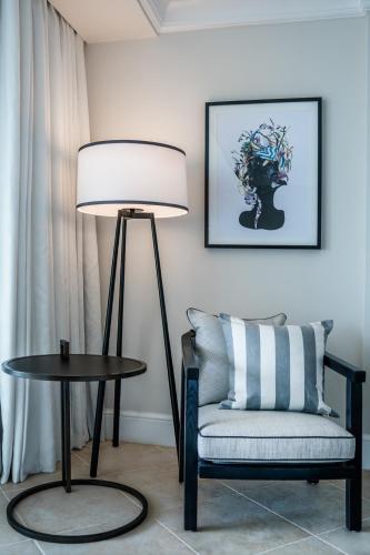 a living room with a table and a chair and a lamp at Fairmont Royal Pavilion Barbados Resort in Saint James