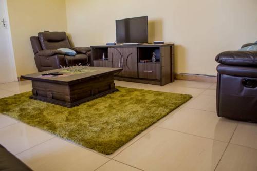 sala de estar con mesa y TV en Lynm Residence en Harare