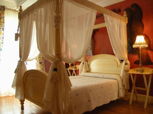 a bedroom with a canopy bed with white curtains at Posada del Indiano in Cidones