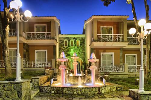 a house with a fountain in front of it at Molfetta Beach Hotel  in Gouvia