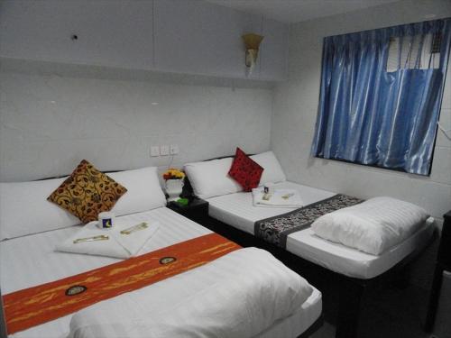 a hotel room with three beds and a window at Paris Guest House in Hong Kong