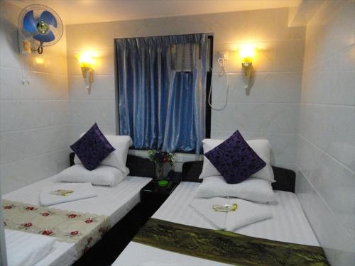 Habitación con 2 camas y ventana con almohadas moradas. en Singh Guest House, en Hong Kong