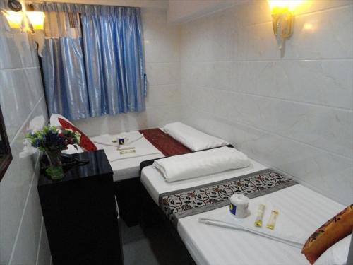 um pequeno quarto com 2 camas numa casa de banho em Singh Guest House em Hong Kong