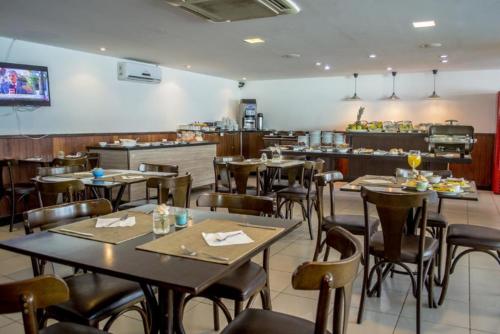 een eetkamer met tafels en stoelen in een restaurant bij Ponta Negra Beach Melo Flat in Natal