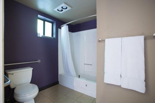 a bathroom with a toilet and a window and towels at Alura Inn in San Jose