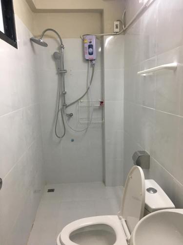 a white bathroom with a shower and a toilet at Maerim Hostel in Chiang Mai