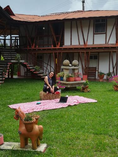 a woman sitting on the grass in front of a house at Hotel El Ganadero in El Total