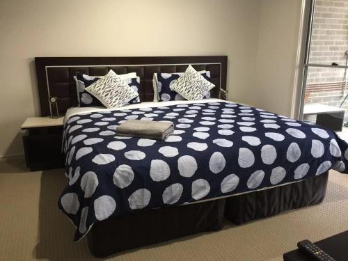 a bedroom with a black and white bed with pillows at Gosford Townhouse in Gosford