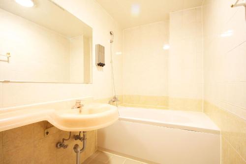 a bathroom with a tub, sink, mirror and bathtub at Business Hotel Busan Station in Busan