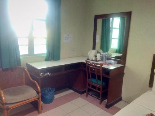 a bathroom with a desk and a mirror and a chair at Arwana Inn Tok Bali in Pasir Puteh