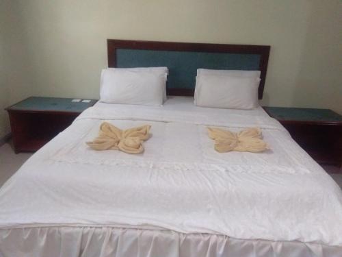 a large white bed with two pillows on it at Arwana Inn Tok Bali in Pasir Puteh