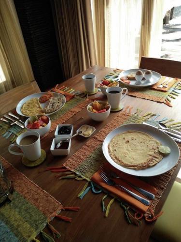 een houten tafel met borden met eten erop bij Villa Bella Vista in Nusa Lembongan