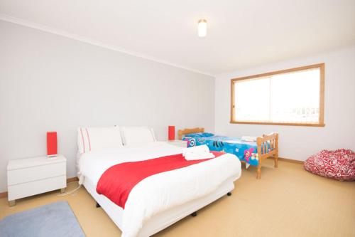 a white bedroom with a large bed and a window at St Helens On The Bay in St Helens