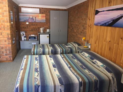 a room with three beds in a brick wall at Kadina Gateway Motor Inn in Kadina